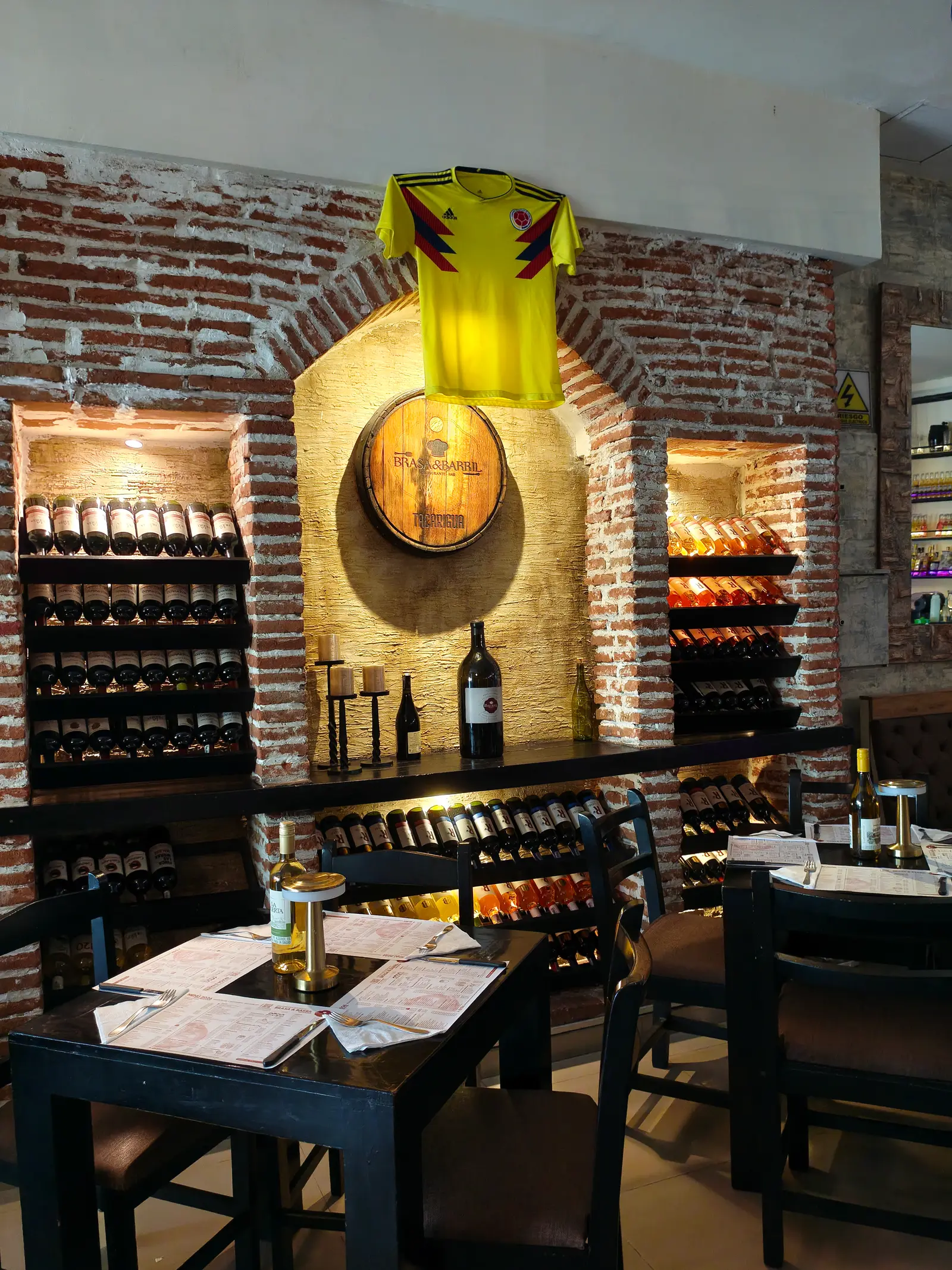 Interior de Brasa y Barril: muro de ladrillo, barril y vinos